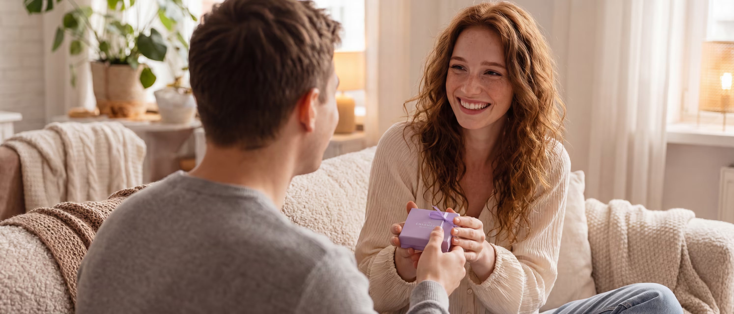 Frau freut sich über Schmuck in einer lavendelfarbenen Geschenkbox von Charmerie