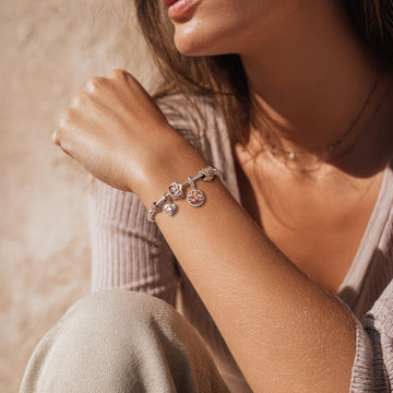 Frau trägt Armband mit Charms Set ROSÉ BLOOM von Charmerie aus 925 Sterling-Silber