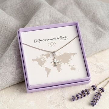 Kette mit Flugzeug-Anhänger aus 925 Silber in Geschenkbox vor Weltkarten-Motiv, Geschenkkarte "Distance means nothing"