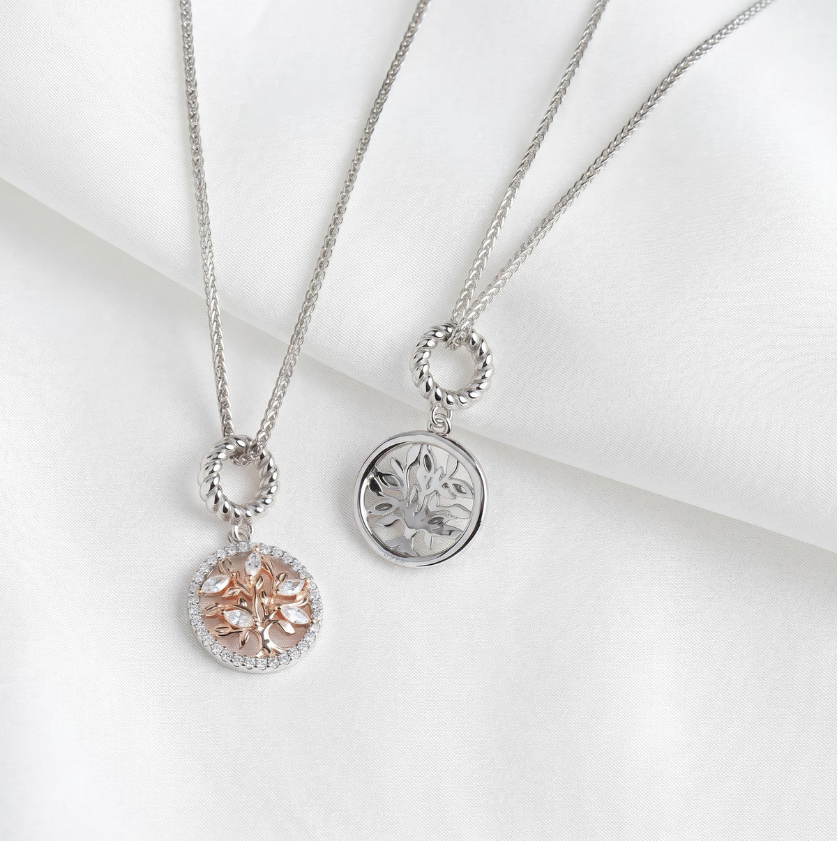 Zwei Ketten mit rundem Lebensbaum-Anhänger aus 925 Silber, eine mit Roségold und Zirkonia, eine in reinem Silber, nebeneinander drapiert