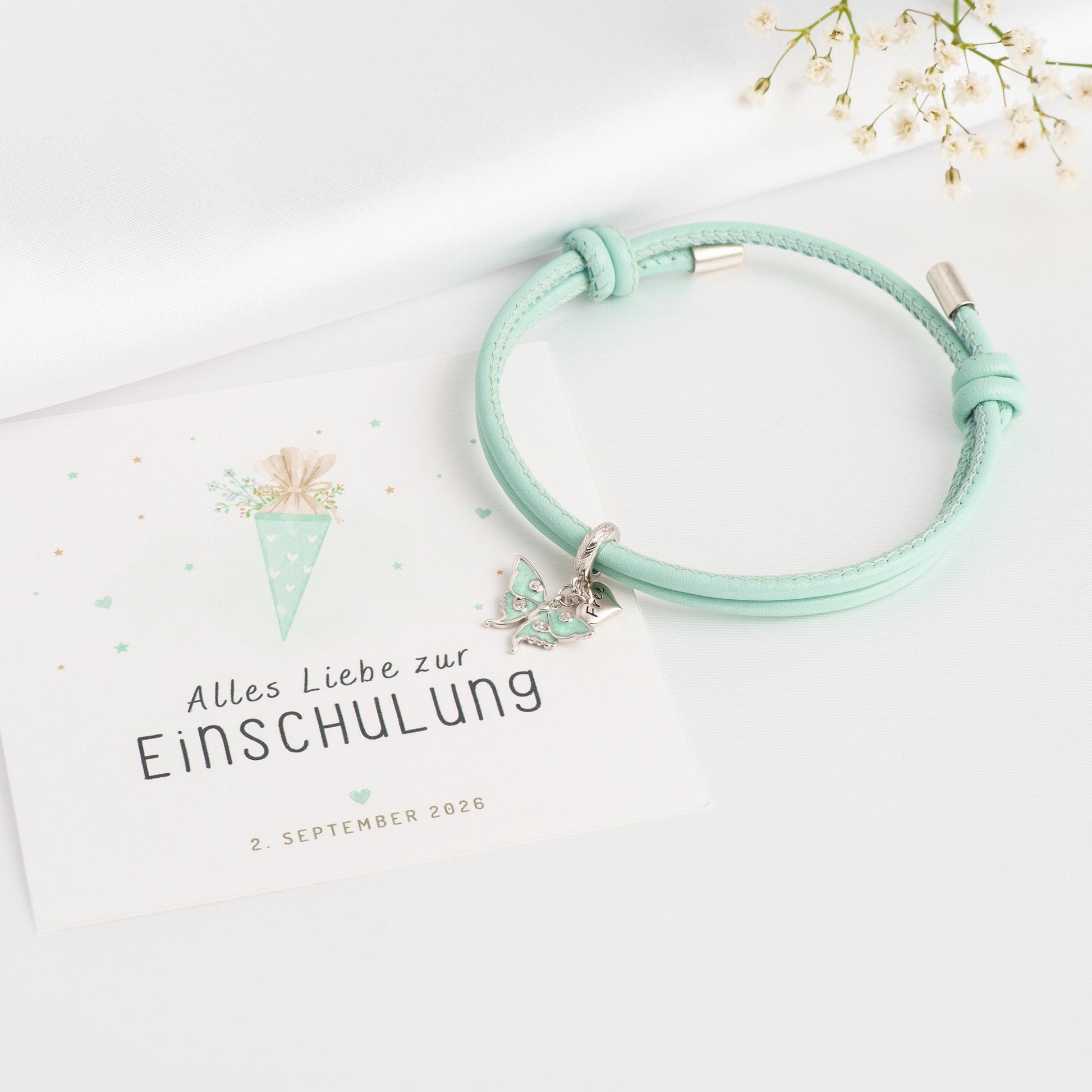 Mintgrünes Lederarmband mit Schmetterling-Charm aus 925 Silber, Geschenkkarte "Alles Liebe zur Einschulung" mit Schultüten-Motiv, 2. September 2026