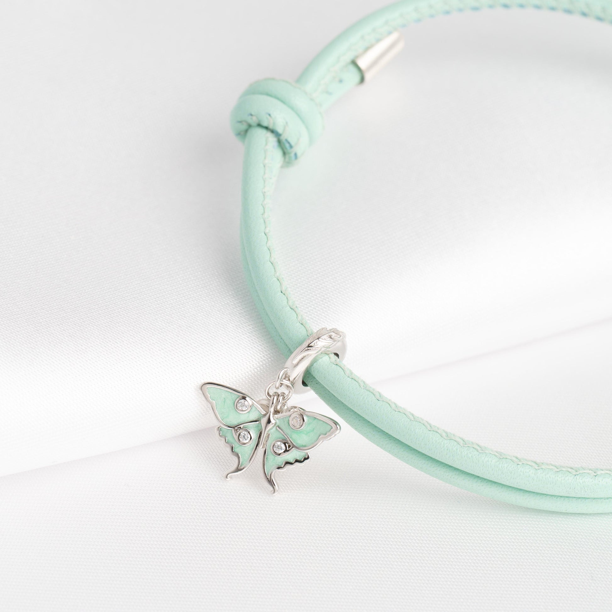 Nahaufnahme des mintgrünen Lederarmbands mit Schmetterling-Charm aus 925 Silber